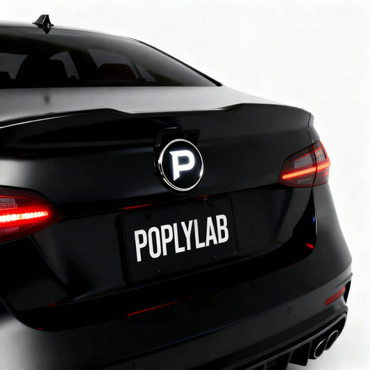 Poply PixelBadge installed on black sedan rear trunk lid — glowing white P logo on programmable LED display, license plate reads POPLYLAB